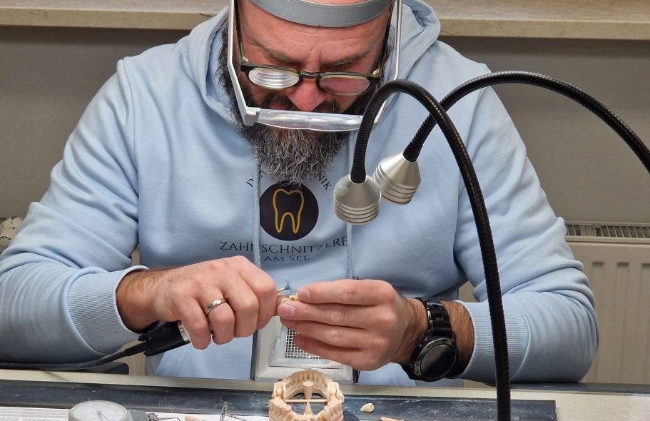 Zahntechnikermeister Christian Schwaebe arbeitet präzise mit Werkzeug an einem Zahnersatz.