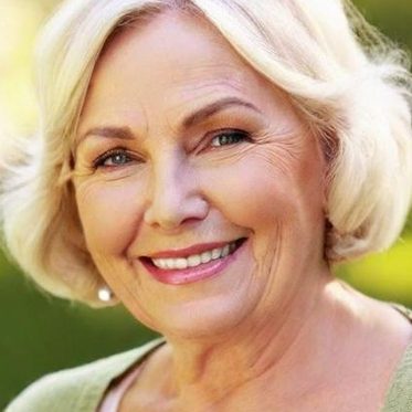 Ältere Frau mit kurzen, blonden Haaren und lächelndem Gesicht, gut sichtbare gepflegte Zähne
